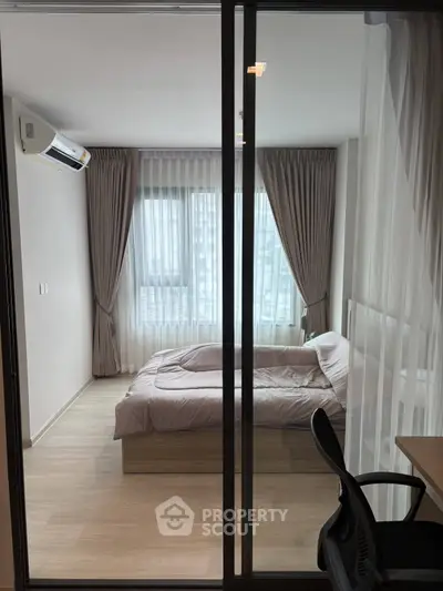 Modern bedroom with large windows and stylish curtains, featuring a comfortable bed and sleek furnishings.