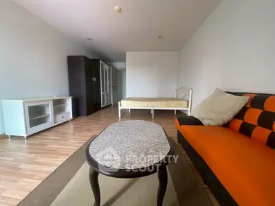 Spacious studio apartment with modern furnishings and wooden flooring.