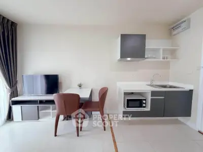 Modern compact kitchen and dining area with sleek cabinetry and natural light.