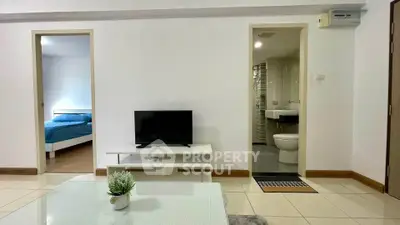 Modern apartment interior with cozy living room and view into bedroom and bathroom.