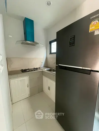 Compact kitchen with modern fridge and gas stove in cozy apartment