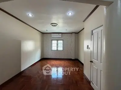 Spacious empty room with wooden flooring and air conditioning, ideal for customization.