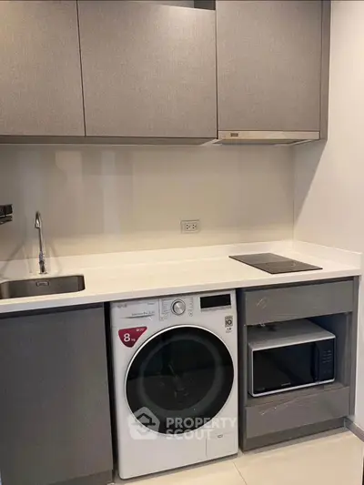 Modern kitchen with integrated appliances including washing machine and microwave, sleek cabinetry, and induction cooktop.
