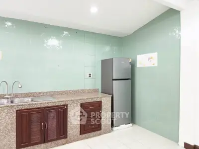 Modern kitchen with sleek fridge and granite countertops in a stylish apartment.
