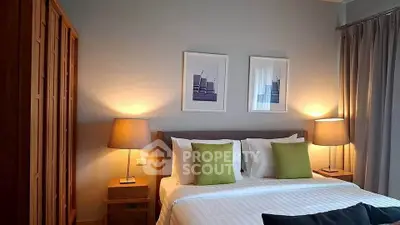 Cozy bedroom with modern decor, featuring a comfortable bed, stylish lamps, and elegant artwork.