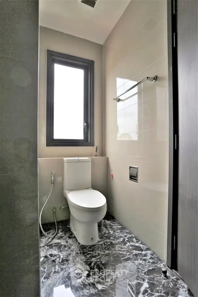 Modern bathroom with marble flooring and large window for natural light.
