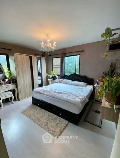 Elegant bedroom with chandelier and large windows, featuring stylish decor and ample natural light.