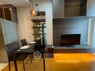Modern dining area with sleek furniture and built-in TV unit in stylish apartment.