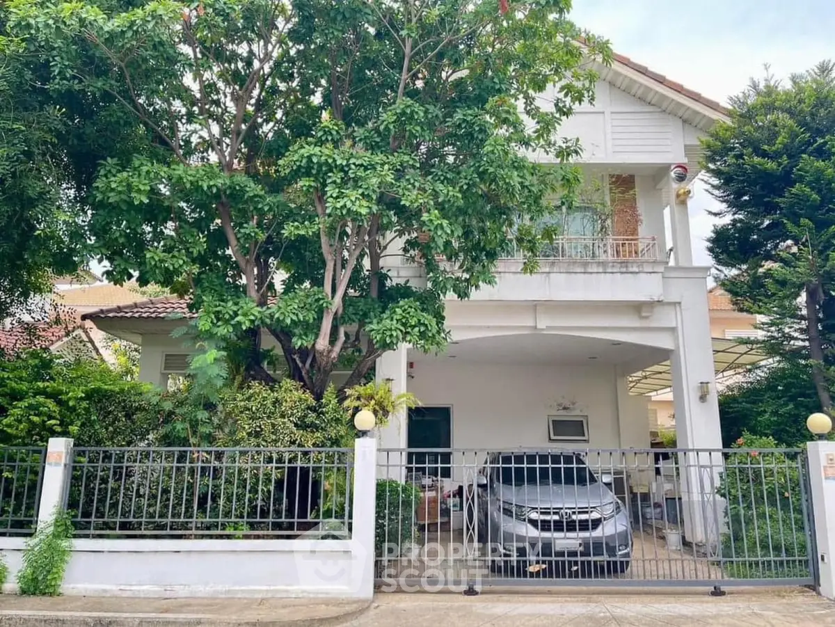 Charming two-story house with lush garden and carport in a serene neighborhood.