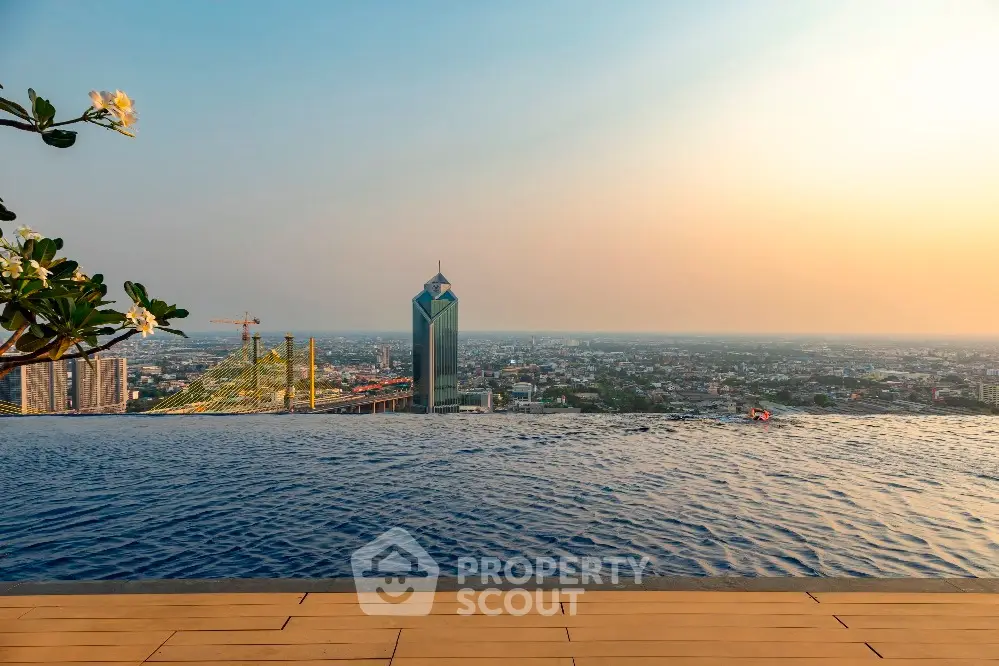 Stunning rooftop infinity pool with panoramic city skyline view at sunset.