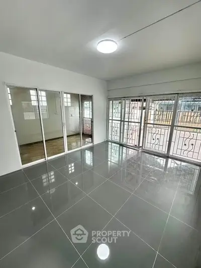 Spacious living room with glossy tiled floors and large windows for natural light.