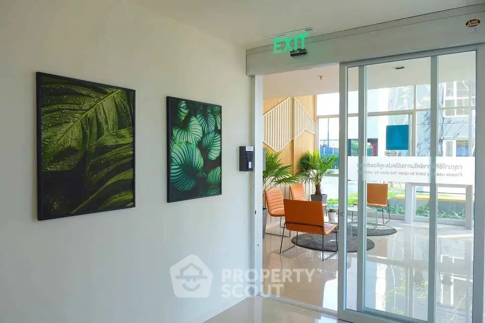 Modern building entrance with stylish decor and glass doors leading to a bright lobby area.