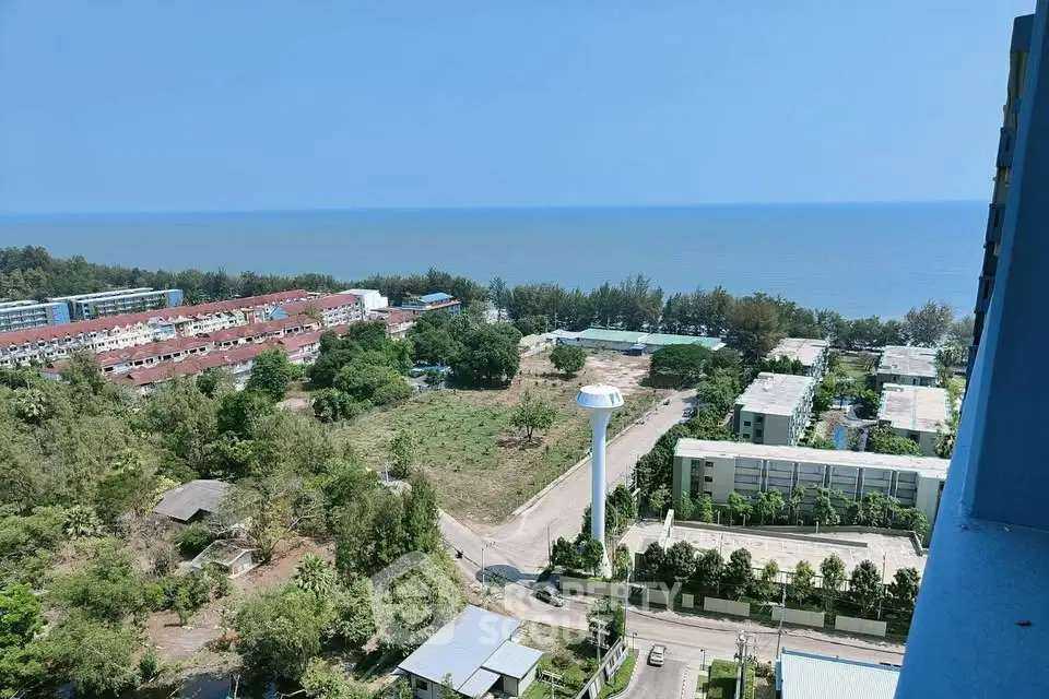Stunning ocean view from high-rise building overlooking lush greenery and residential area.