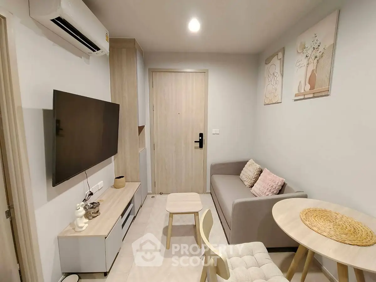 Modern living room with stylish decor, featuring a cozy sofa, wall-mounted TV, and elegant artwork.