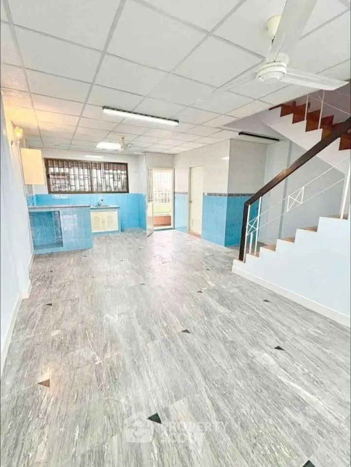 Spacious open-plan living area with modern kitchen and staircase, ideal for family gatherings.