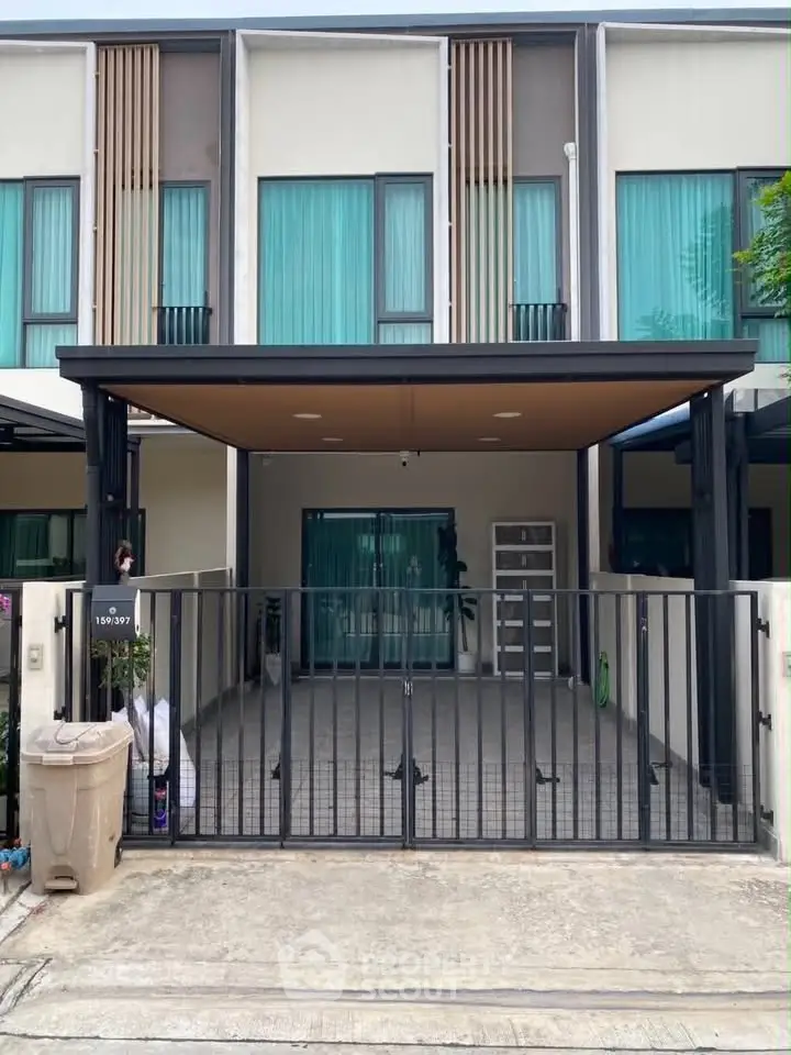 Modern townhouse exterior with gated entrance and covered parking area.