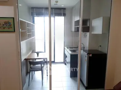 Modern kitchen with sleek design, featuring a compact layout and ample natural light from large windows.