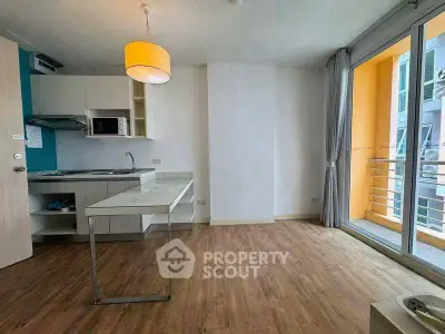 Modern apartment with open kitchen and balcony, featuring wooden flooring and ample natural light.
