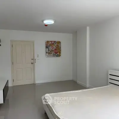 Spacious minimalist bedroom with modern decor and ample natural light.