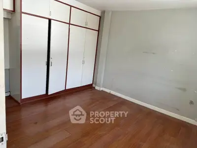 Spacious empty room with wooden floor and built-in wardrobe, ideal for customization.