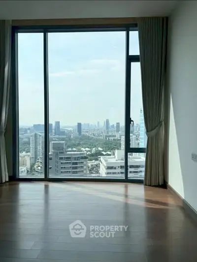 Spacious room with floor-to-ceiling windows offering stunning cityscape views.