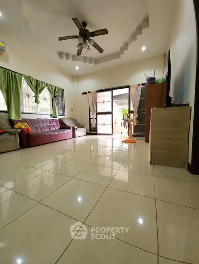 Spacious living room with tiled floor, ceiling fan, and natural light