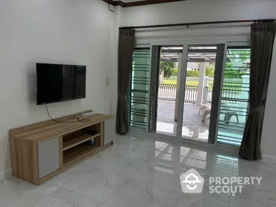 Spacious living room with modern TV setup and large sliding glass doors opening to patio.