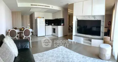Spacious modern living room with open kitchen and elegant dining area, featuring a large TV and stylish decor.