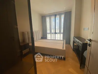 Spacious bedroom with large window and elegant furnishings in modern apartment.