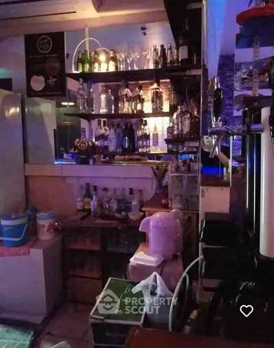 Cozy home bar with shelves of liquor bottles and glassware, perfect for entertaining guests.