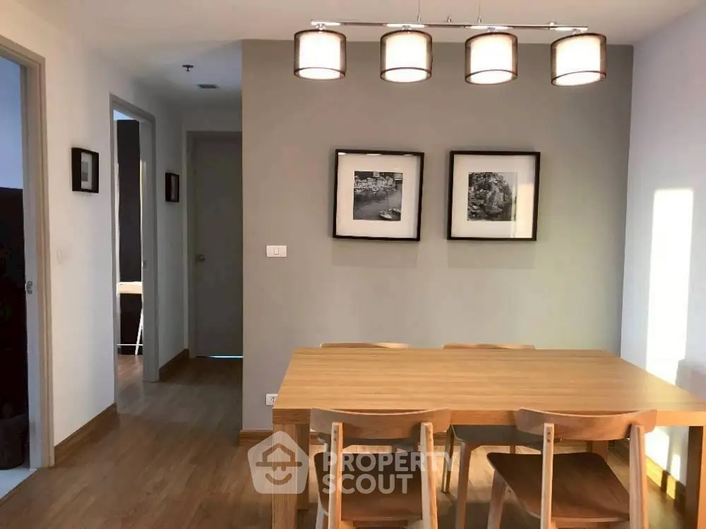 Modern dining area with wooden table and chairs, stylish lighting, and framed wall art.