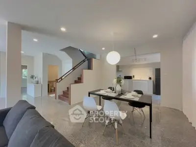 Modern open-plan living room with dining area and staircase in stylish home