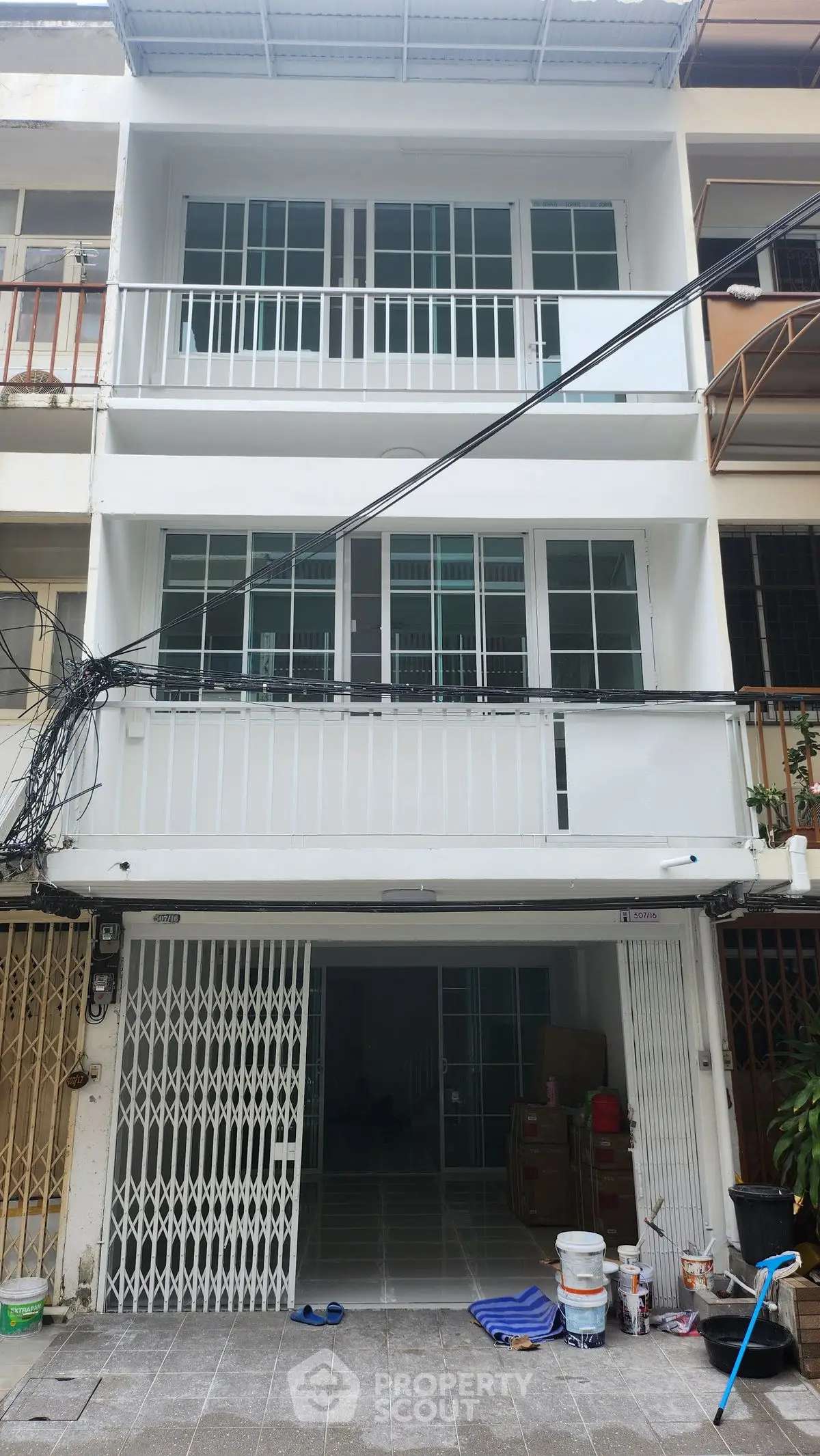 Modern three-story townhouse with spacious balconies and secure garage in urban setting.