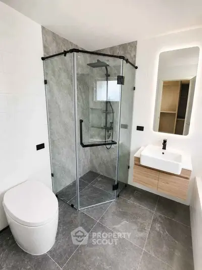 Modern bathroom with glass shower, sleek sink, and contemporary toilet design.
