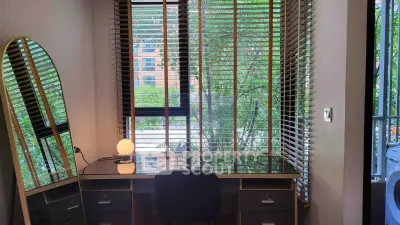 Chic study nook with modern desk and large mirror, overlooking lush greenery through stylish blinds.