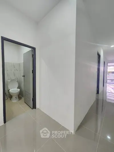 Spacious hallway with modern tiled flooring and a glimpse of a bathroom, ideal for contemporary living.