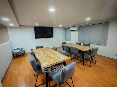 Modern conference room with wooden tables and gray chairs, ideal for meetings.