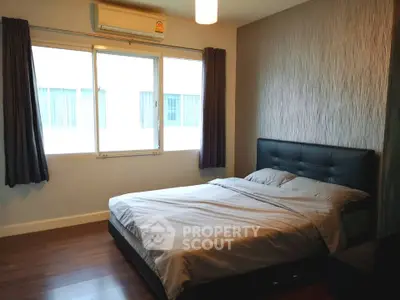 Cozy bedroom with modern decor and ample natural light from large windows.