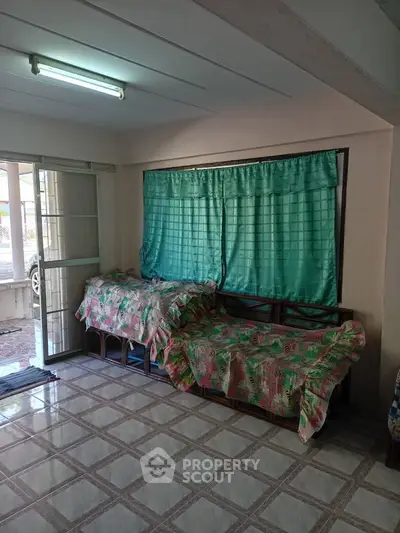 Cozy living room with tiled floor and large window, featuring comfortable seating and natural light.