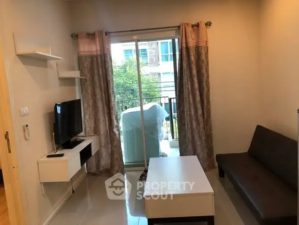 Cozy living room with modern decor and balcony access in urban apartment.