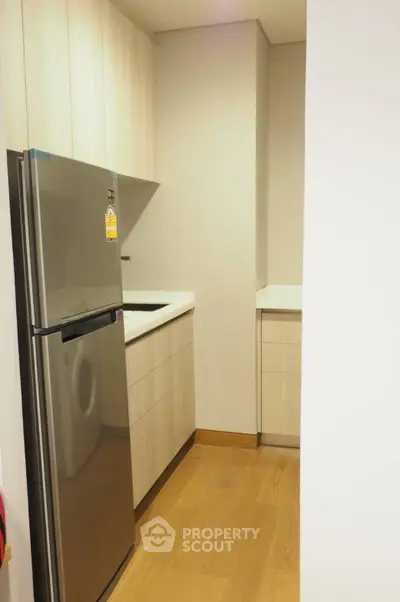 Modern kitchen with sleek stainless steel fridge and light wood cabinetry