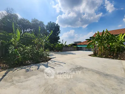 Spacious outdoor area with lush greenery and clear blue sky, perfect for relaxation and outdoor activities.