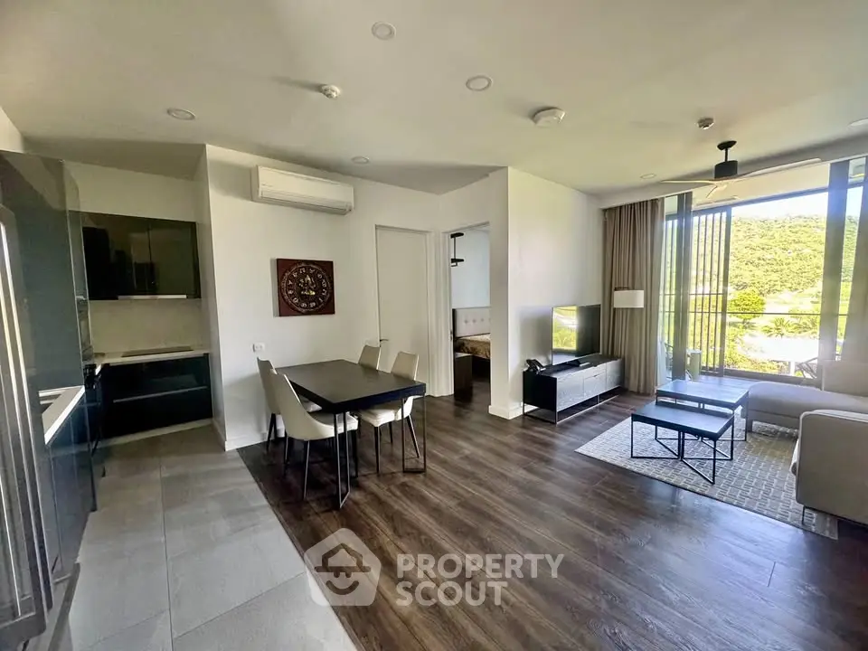 Spacious modern living room with dining area and scenic view, featuring sleek furniture and natural light.