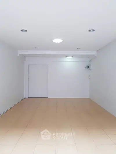 Spacious empty room with tiled flooring and recessed lighting, ideal for customization.