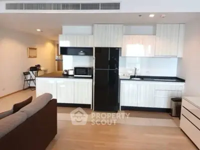 Modern kitchen with sleek cabinetry and black appliances in open layout apartment.