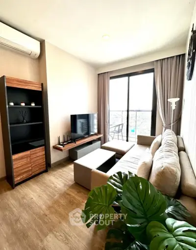 Modern living room with large window and stylish decor, featuring a cozy sofa and entertainment center.