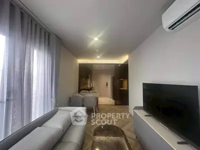 Modern living room with sleek design and air conditioning, featuring a cozy sofa and flat-screen TV.