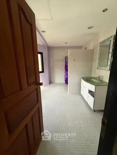 Spacious bathroom with modern fixtures and elegant tile flooring, featuring a large mirror and ample natural light.