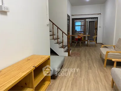 Charming living room with wooden flooring and staircase, cozy seating, and dining area.