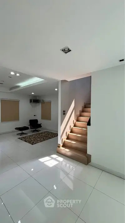 Modern interior with sleek staircase and minimalist design, featuring bright natural light and stylish seating area.